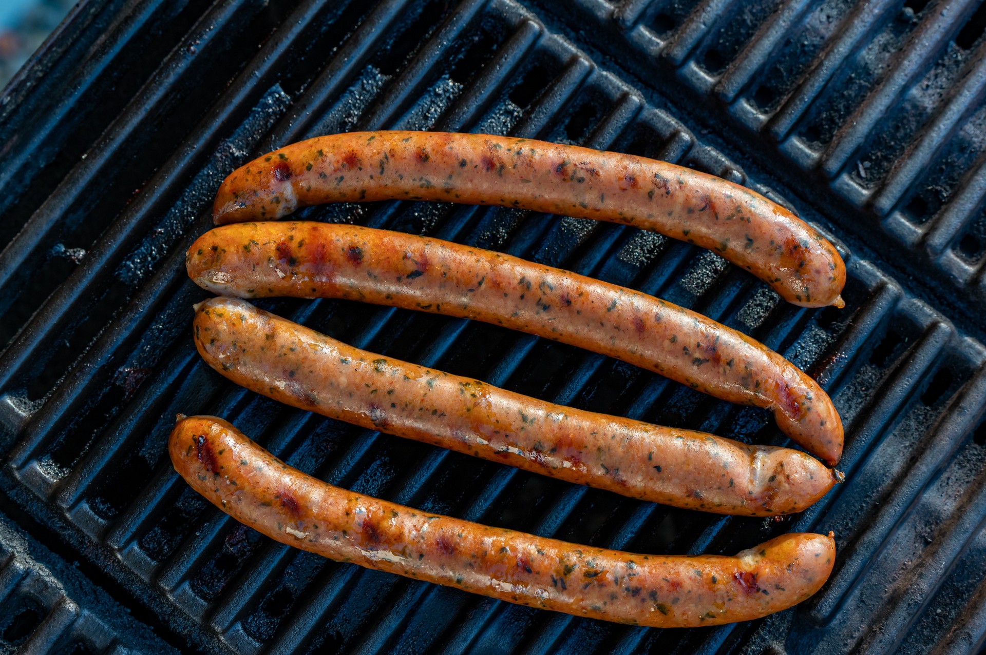 Four spiced sausages heated on gas grill